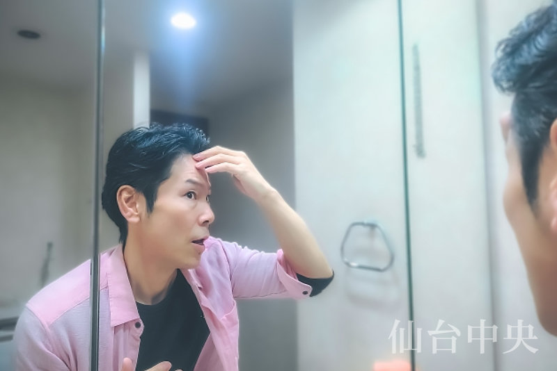 薄毛が気になり鏡を見る50歳代男性